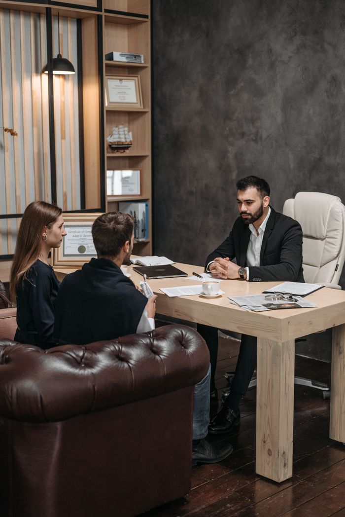 Crafting Captivating Headlines: Your awesome post title goes here A professional business meeting with three people discussing documents in an office setting.