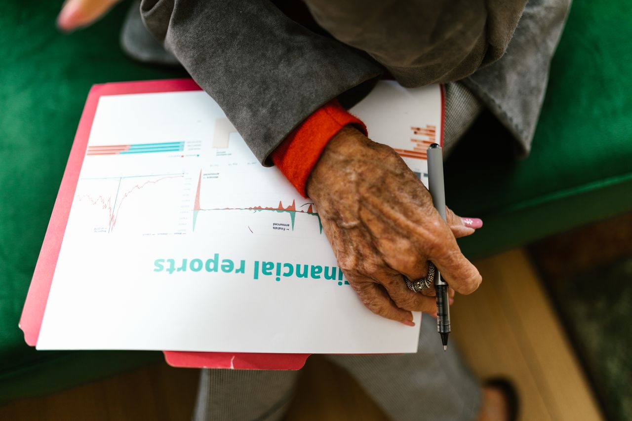 The Art of Drawing Readers In: Your attractive post title goes here Close-up of an elderly woman holding a pen with a financial report.